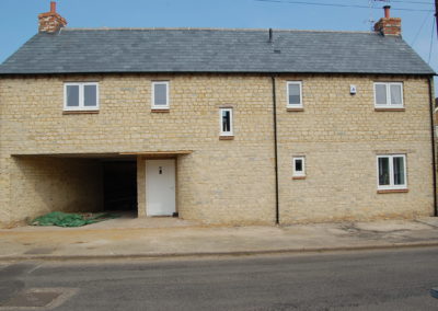 Country Hardwood white timber windows and front door installed in modern stone built house with slate roof.